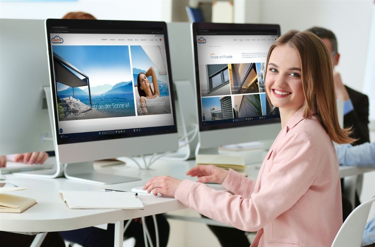 Frau sitzt im Büro am PC und lächelt